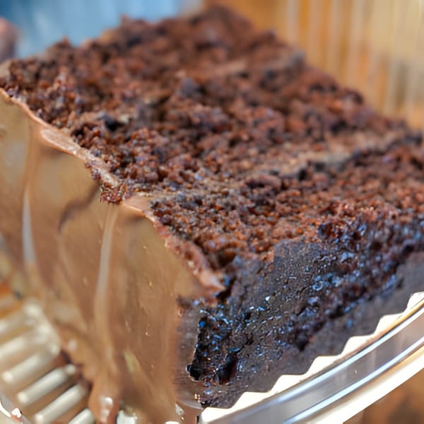 A close-up of a rich chocolate cake slice with chocolate frosting and crumb topping.