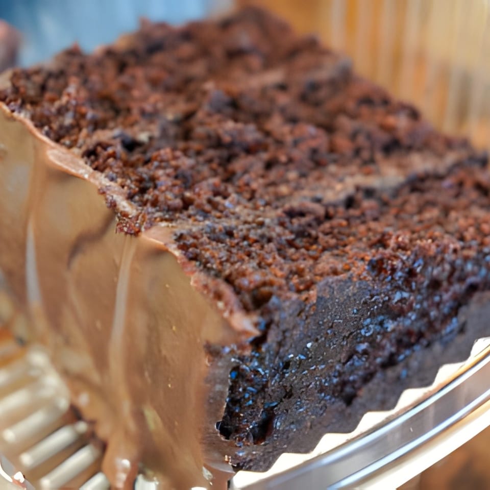 A close-up of a rich chocolate cake slice with chocolate frosting and crumb topping.