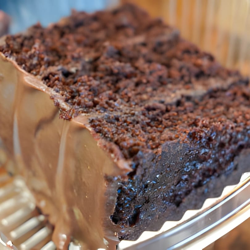 A close-up of a rich chocolate cake slice with chocolate frosting and crumb topping.