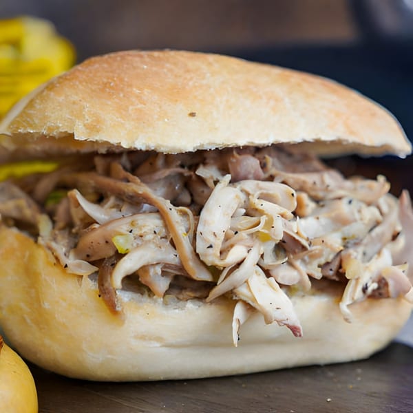 Close-up of a sandwich filled with shredded chicken or mushrooms on a wooden surface.